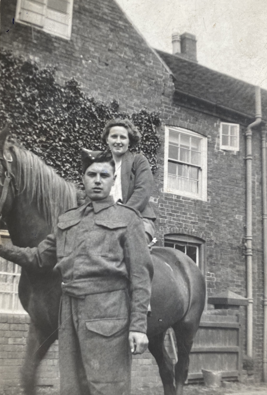 Photo of Tom standing next to woman on horseback, taken on the farm where he worked. 