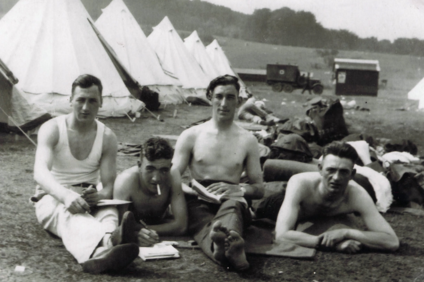 David lying down on chest with cigarette in mouth, between two comrades and a third comrade pictured at the end. Identities of the other three men are unknown.